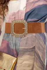 Cinturón ancho elástico con sección frontal en símil gamuza color marrón y hebilla metálica dorada de diseño texturizado.