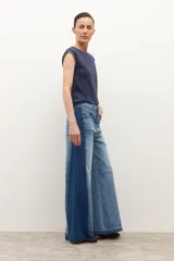 Jean wide leg bicolor en tonos de gris oscuro, con paneles laterales más oscuros y ruedo deshilachado.