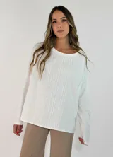 Blusa de manga larga en color blanco, con cuello redondo y detalle de alforzas verticales en el frente. Presenta un corte holgado y fluido.