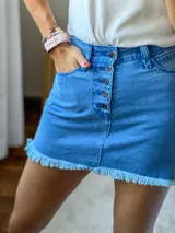 Minifalda de jean azul con botones frontales y ruedo desflecado.