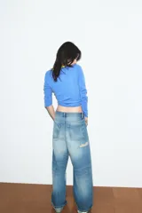 Chaqueta de punto color azul, con cuello redondo y manga larga. Presenta acabados en contraste de color verde neón y cierre frontal cruzado con botones.