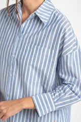 Camisa de algodón con rayas verticales celestes y blancas, de corte oversize, cuello camisero, manga larga y bolsillo aplicado en el pecho.