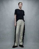 Pantalón de cuero de tiro medio y corte recto, en color beige. Presenta flecos largos de color negro en los laterales de ambas piernas, aportando movimiento y un estilo western.