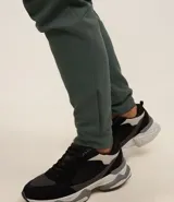 Pantalón deportivo de corte ajustado, confeccionado en tejido de poliéster texturizado color negro. Presenta cintura elástica con cordón de ajuste, bolsillos laterales con cierre y puños elásticos en los tobillos.