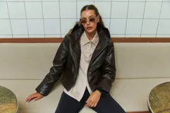 Campera marrón de cuero sintético con cierre frontal asimétrico y cuello con solapa.