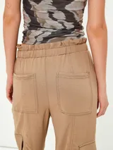 Pantalon cargo color tostado con cintura elastizada y cordón ajustable. Presenta bolsillos laterales tipo cargo y costuras visibles a lo largo de las piernas.