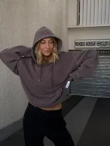 Buzo canguro marrón con capucha y cordones, de corte amplio y estilo urbano.