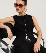 Chaleco negro de sastrería con cuello redondo, cierre frontal con botones dorados y bajo estructurado con recortes anatómicos.