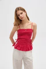 Top de algodón con diseño estampado de cuadros vichy en tonos celeste y blanco, corte al cuerpo con escote recto y tirantes finos. Presenta cuerpo fruncido tipo smock con cordones ajustables en los laterales que forman un pequeño volado en el ruedo.