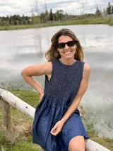 Vestido corto sin mangas de denim azul, con diseño holgado y detalle de nido de abeja (smock) hecho a mano con costuras en hilo marrón en la parte superior.