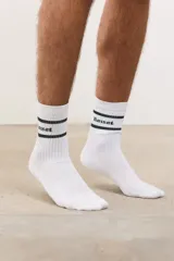 Medias altas de algodón con diseño acanalado, color blanco con dos líneas horizontales oscuras y logo estampado.