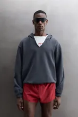Sudadera de algodón con interior de rizo, corte relaxed fit, color gris oscuro. Cuenta con cuello con capucha y abertura frontal en V, manga larga y bajo con puños elásticos.