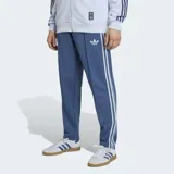 Pantalón deportivo Adidas de corte clásico, color azul con las icónicas tres tiras blancas laterales. Presenta el logo del Trifolio bordado en la parte superior y cordón de ajuste en la cintura.