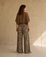 Pantalón wide leg de tiro alto con cintura elastizada y bolsillos laterales, confeccionado en tela ligera con estampado animal print tipo leopardo en tonos marrones y beige.