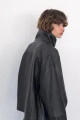 Cazadora de corte oversize confeccionada en 100% piel. Presenta cuello subido, manga larga con hombro caído y cierre frontal mediante cremallera y botones a presión ocultos bajo una solapa. Incluye bolsillos laterales ocultos en las costuras y forro interior.