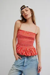 Musculosa de cuadros vichy rojos y blancos, con cuerpo fruncido elastizado, escote recto, tirantes finos y diseño peplum con vuelo en el ruedo.