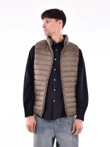 Chaleco acolchado tipo puffer, color tostado, con cuello alto y cierre frontal completo.