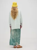 Pareo-pollera larga envolvente de viscosa, color verde menta con estampado abstracto en tonos anaranjados y azulados. Presenta un nudo lateral para ajuste.