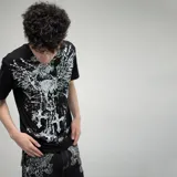 Remera negra de algodón con estampado frontal en blanco que incluye un cráneo con alas, cruces y detalles góticos. Corte oversize.