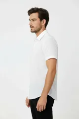 Camisa de algodón blanca de manga corta, con cuello camisero y cierre frontal de botones.