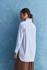 Camisa de calce relajado color celeste, con escote en V y cuello mao, mangas largas y largo extendido.