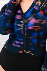 Malla entera de lycra con estampado abstracto en tonos azules, naranjas y violetas. Tiene cierre frontal con cremallera y mangas largas.