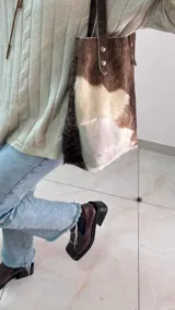 Bolso tipo tote de cuero con pelo color marrón y blanco, con manijas de cuero crudo.