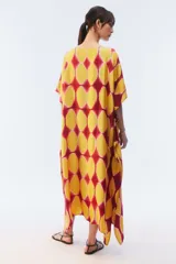 Kaftan maxi amplio de color amarillo, con escote redondo, mangas cortas y ruedo irregular. Presenta un diseño estampado a cuadros con efecto teñido.