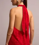 Túnica larga roja con textura jacquard de formas geométricas cuadradas, cuello halter con lazo para anudar y espalda descubierta.