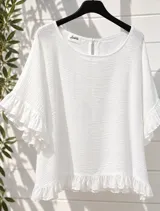 Blusa blanca de tela liviana y fresca, con mangas cortas abullonadas terminadas en volados y detalle de volado en el ruedo. Presenta escote redondo con pequeña abertura y botón en la parte posterior.
