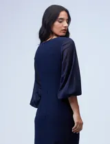 Vestido azul de RM Richards en seda fría, con escote en V cruzado, cintura drapeada, mangas largas de gasa y aplique de botones en el lateral.