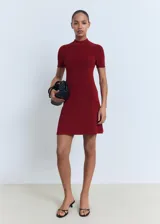 Vestido corto de tejido de punto fino en color bordó, con cuello perkins y mangas cortas. Presenta un diseño evasé que se ajusta suavemente al cuerpo.