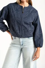 Campera tipo bomber color azul, con cierre frontal y diseño de bordado floral en toda la prenda. Presenta puños y ruedo con elástico, y un corte holgado.