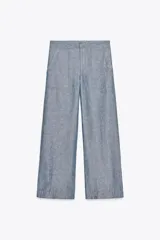 Pantalón de tiro bajo color azul con textura de lino, de pierna ancha, con bolsillos delanteros y traseros. Cierre frontal con cremallera, botón y ganchos metálicos.