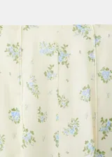 Falda midi evasé de color blanco con estampado floreado en tonos azules y verdes. Cuenta con cierre lateral y forro interior.