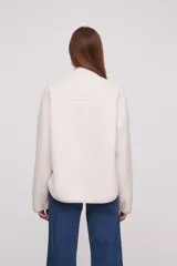 Campera blanca de poliéster con cuello mao, cierre con botones a presión y diseño acolchado en la parte superior.