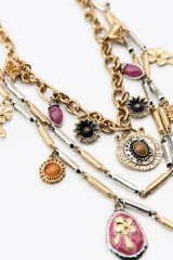 Pack de tres collares superpuestos con cadenas mixtas en tonos dorado y plateado. Incluyen múltiples dijes colgantes con piedras de colores (turquesa, rosa, ámbar, violeta) y motivos florales y de insectos.