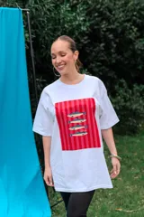 Remerón de algodón blanco con corte oversize y cuello redondo, que presenta un estampado frontal con diseño de una lata de sardinas sobre fondo de rayas.