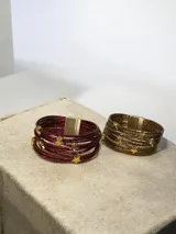 Brazalete de múltiples tiras finas con acabado metalizado, decorado con apliques de estrellas doradas y cierre imantado.