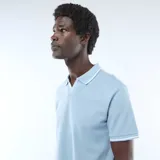 Remera de piqué de algodón color azul claro, con cuello polo sin botones y detalles de líneas blancas en el borde del cuello y las mangas.