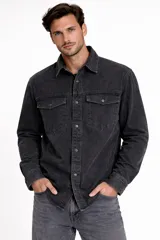 Camisa de jean con efecto lavado, manga larga, cuello clásico y cierre frontal con botones. Presenta dos bolsillos frontales con solapa y botones.