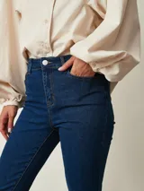 Jean chupín negro de tiro alto, confeccionado en denim con cinco bolsillos tradicionales y cierre frontal con botón y cremallera.