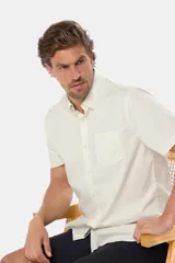 Camisa lisa de manga corta color crema, confeccionada en 100% algodón, con cuello abotonado y un bolsillo en el pecho.