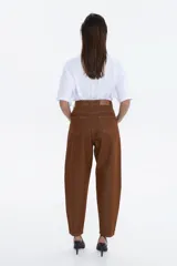 Pantalón de jean de tiro alto, color verde oliva desgastado, con calce relajado y piernas que se afinar hacia el tobillo.