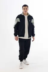 Campera negra de nylon con recortes en forma de V en color gris en las mangas. Tiene cuello mao, cierre frontal, puños y cintura elásticos, bolsillos laterales y logo estampado en el pecho y en la manga izquierda.