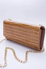 Cartera tipo sobre color beige con textura granulada y correa de cadena dorada.