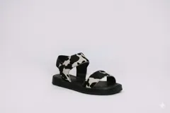 Sandalias bajas con suela negra y tiras de cuero con estampado de vaca.