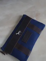 Sobre tipo cartuchera de lona con estampado de camuflaje y terminaciones en cuero marrón.