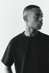 Remera negra de punto pesado con cuello redondo ribeteado, hombros caídos y bajo recto. Corte holgado confeccionada con tejido funcional COOLMAX®, una fibra de poliéster de secado rápido que elimina la humedad y regula la temperatura corporal.