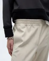 Pantalón tipo babucha sastrero negro, de tiro medio y corte pitillo hasta el tobillo. Presenta cintura elastizada, cartera falsa, bolsillos laterales y raya de aplomo en las piernas.